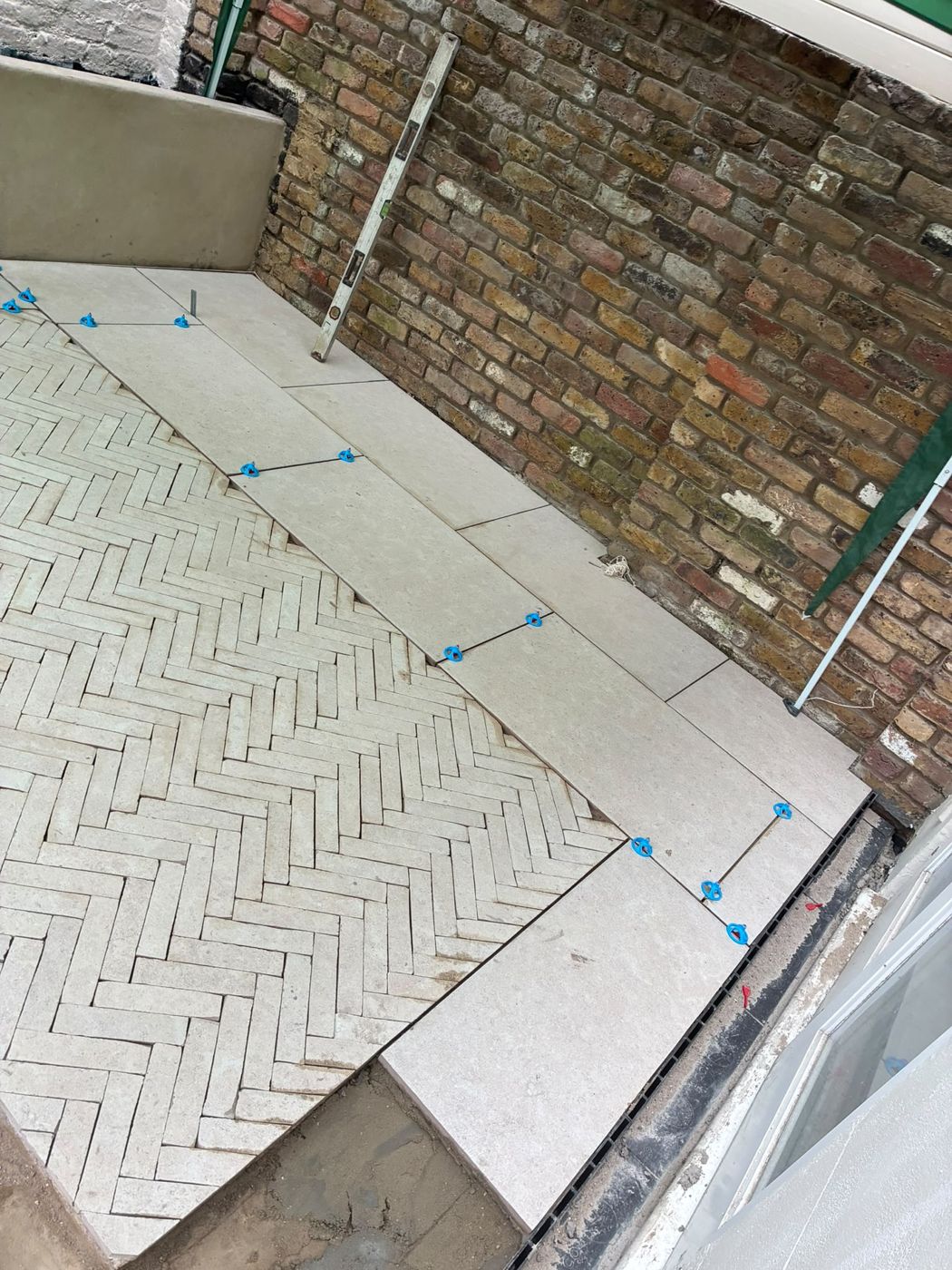 Porcelain border bands laid against the herringbone with levelling clips