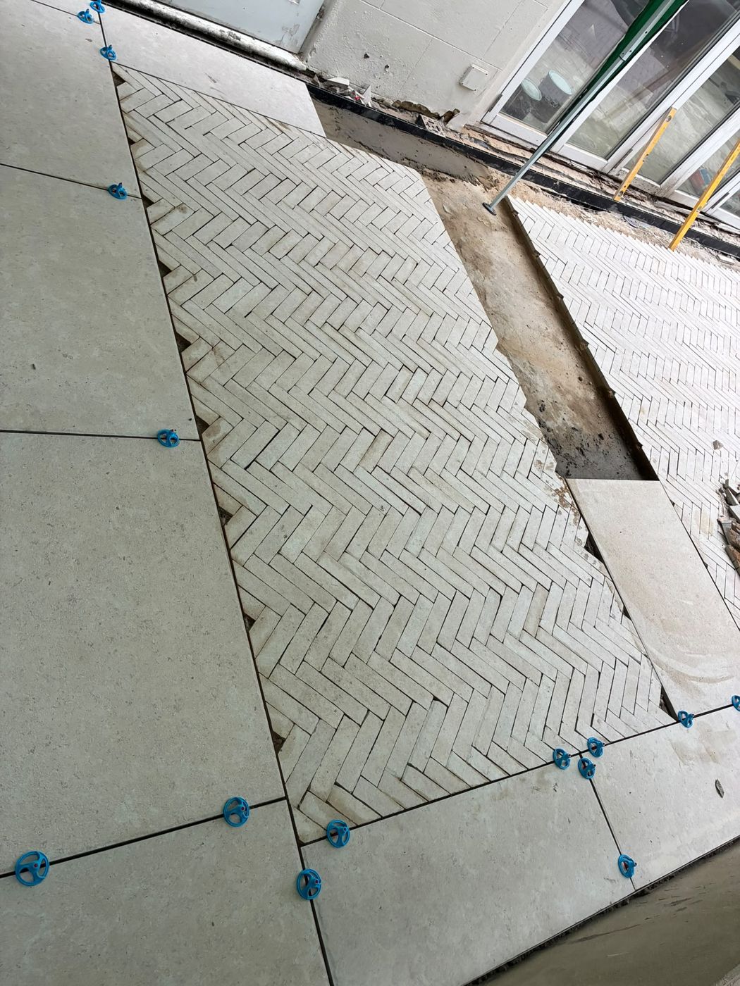 Central herringbone field framed by large-format porcelain